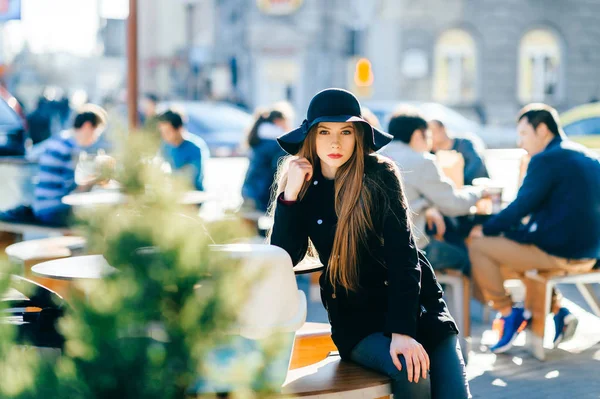 时髦的年轻女子在帽子休息在街上的长椅上 — 图库照片