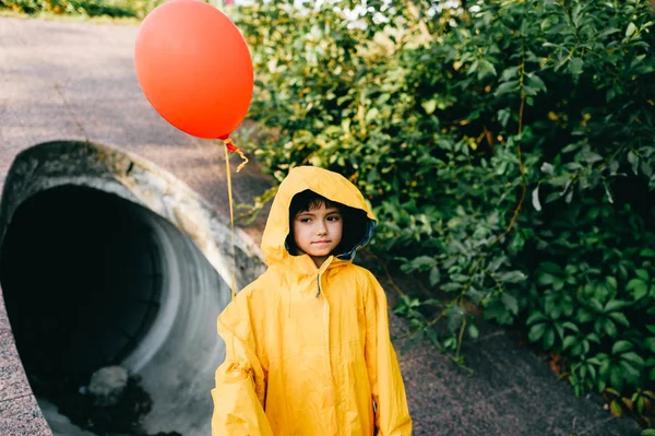 Маленькая Девочка Огромном Желтом Плаще Красным Шаром Против Канализационной Трубы — стоковое фото