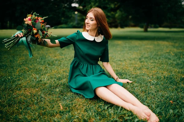 年轻的红头发女人在绿色礼服与夏天的花花束 — 图库照片