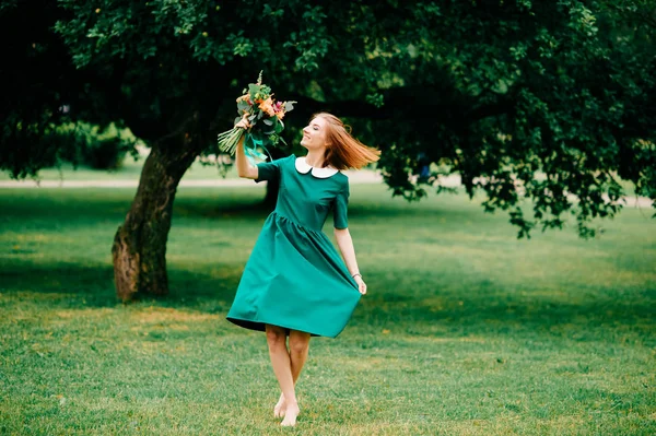夏の花の香りと緑のドレスの若い赤毛の女性 — ストック写真
