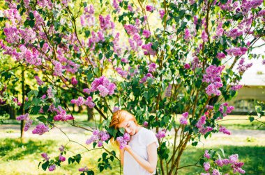 çiçeklenme ile Lila park çalıların arasında genç çekici kadın