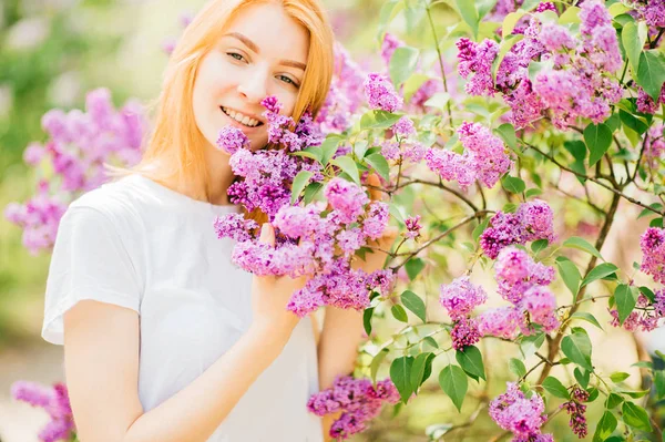 ライラック咲く公園の茂みで若い魅力的な女性 — ストック写真