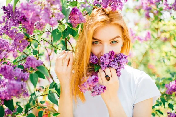 ライラック咲く公園の茂みで若い魅力的な女性 — ストック写真