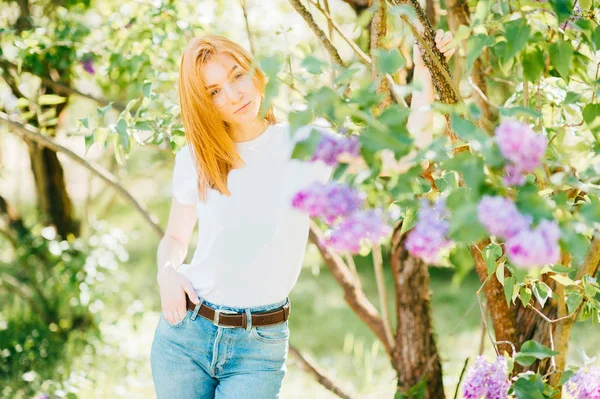 ライラック咲く公園の茂みで若い魅力的な女性 — ストック写真