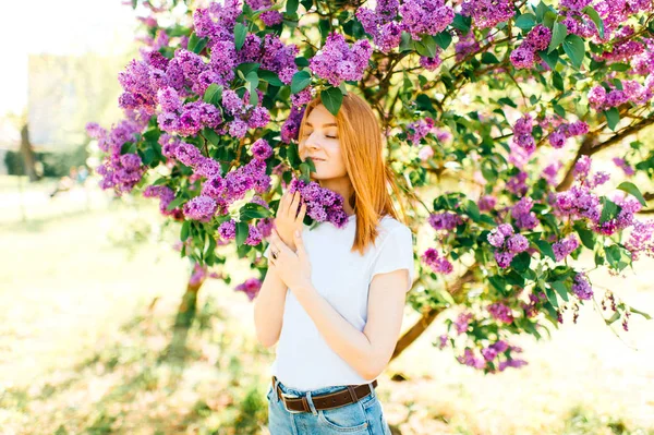ライラック咲く公園の茂みで若い魅力的な女性 — ストック写真