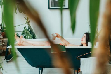 Genç güzel kadın boş Vintage dökme demir banyoda yatıyor