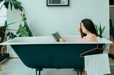 Genç güzel kadın boş Vintage dökme demir banyoda yatıyor