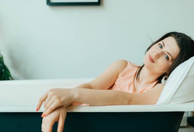 Genç güzel kadın boş Vintage dökme demir banyoda yatıyor