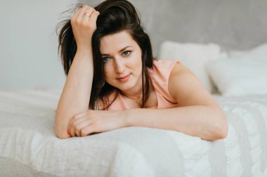 Güzel esmer kadın sabah evde beyaz yatakta yatan