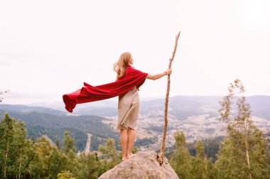 kadın Kırmızı pelerinli bir taş üzerinde duran ve dağlar seyir