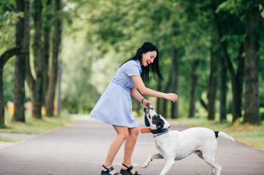 neşeli genç kadınla mavi elbiseli yaz Park büyük siyah ve beyaz köpek