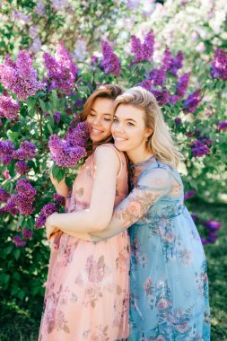 güzel genç ikiz kardeşler çiçeklenme içinde farklı elbiseler Botanik Bahçesi yaz