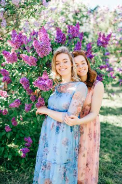 güzel genç ikiz kardeşler çiçeklenme içinde farklı elbiseler Botanik Bahçesi yaz