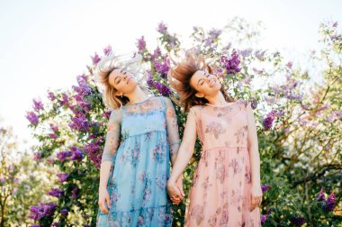 güzel genç ikiz kardeşler çiçeklenme içinde farklı elbiseler Botanik Bahçesi yaz