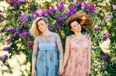 güzel genç ikiz kardeşler çiçeklenme içinde farklı elbiseler Botanik Bahçesi yaz