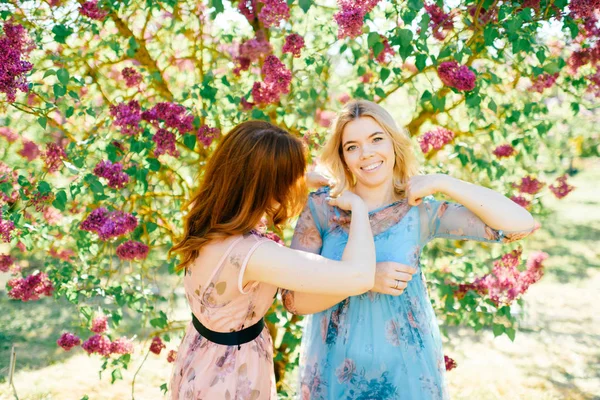 開花の別のドレスで魅力的な双子姉妹夏の植物園 — ストック写真