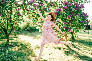yaz çiçek açan parkta atlama pembe elbiseli güzel genç kız