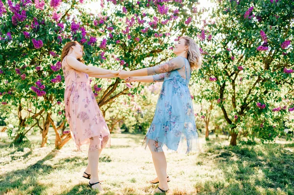 Молодые Сёстры Близнецы Разных Платьях Веселятся Цветущем Летнем Ботаническом Саду — стоковое фото