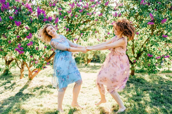 Молодые Сёстры Близнецы Разных Платьях Веселятся Цветущем Летнем Ботаническом Саду — стоковое фото