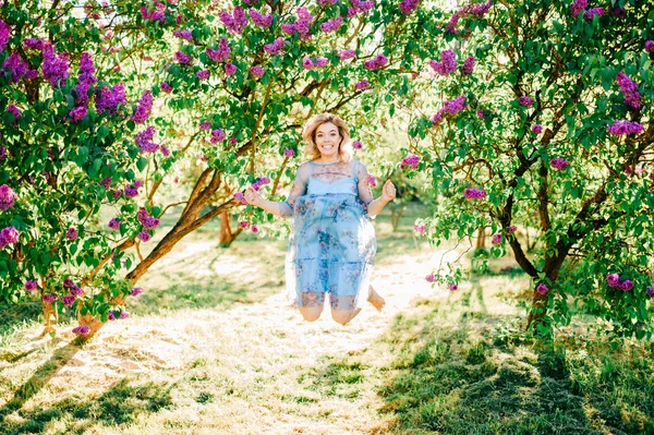 夏咲く公園でジャンプ青いドレスの美しい少女 — ストック写真