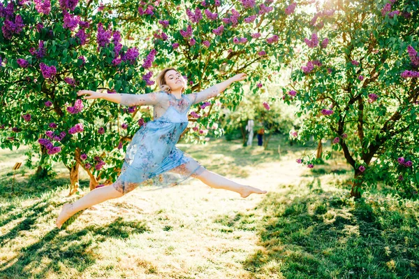 Güzel Genç Kız Mavi Elbiseli Yaz Çiçek Açan Parkta Atlama — Stok fotoğraf
