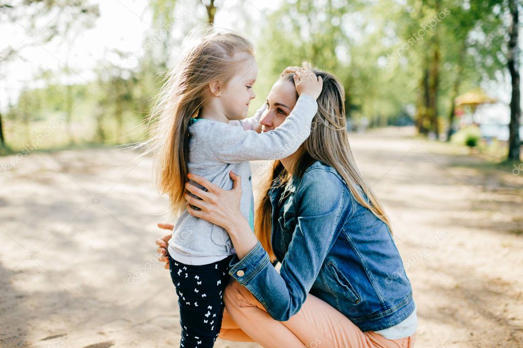 portrait of young mother and little daughter in park