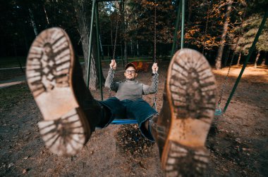 Bahçesi yaz parkta salıncakta sallanan yetişkin adam