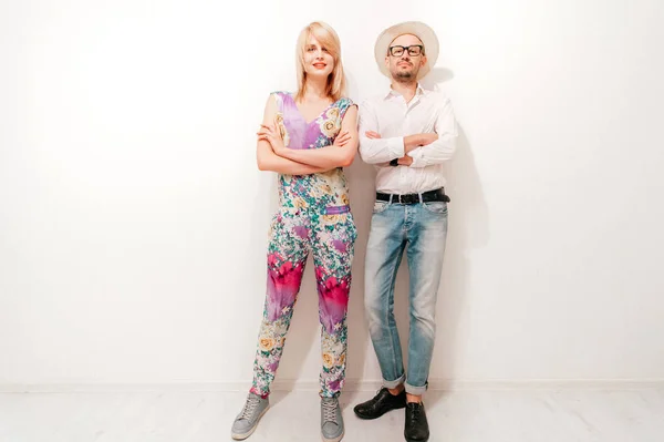 fashionable couple in trendy clothes standing at white wall at home