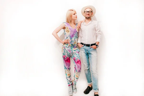 fashionable couple in trendy clothes standing at white wall at home