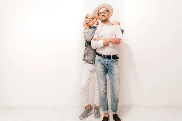 家で白い壁に立っているトレンディな服のおしゃれなカップル — ストック写真