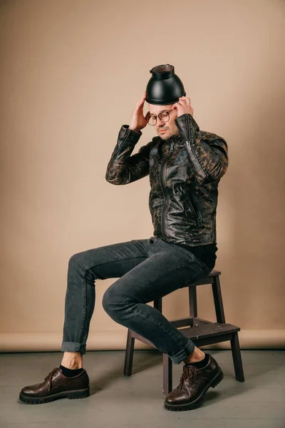 スタジオでポーズの頭の上の黒ポットでファッショナブルな衣料品の男 — ストック写真