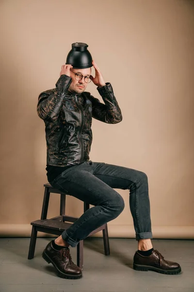 スタジオでポーズの頭の上の黒ポットでファッショナブルな衣料品の男 — ストック写真