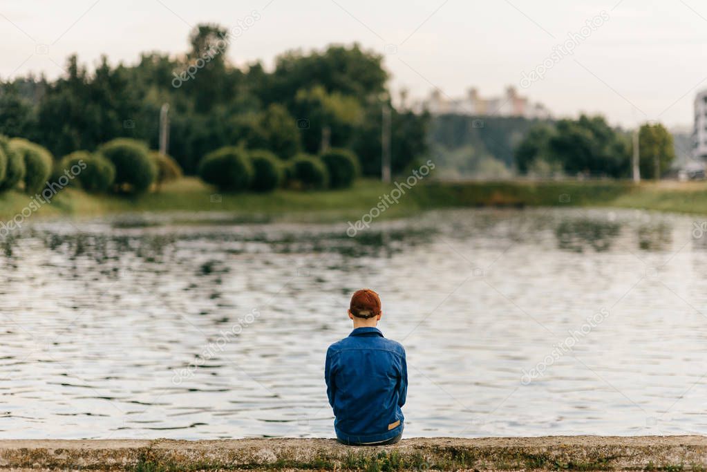 lonely man sitting on edge of embankment outdoor