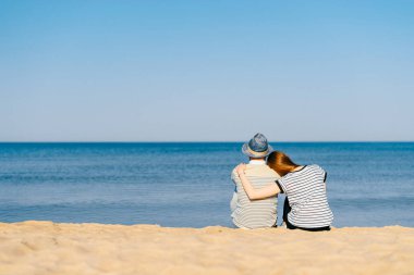 kumsalda birlikte oturan ve okyanus ufka bakarak aşık Çift