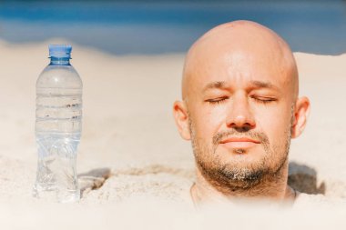 kel adam tarafından su şişe ile plajda kuma gömülü kısmi görünümünü