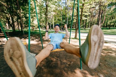 Bahçesi yaz parkta salıncakta sallanan yetişkin adam