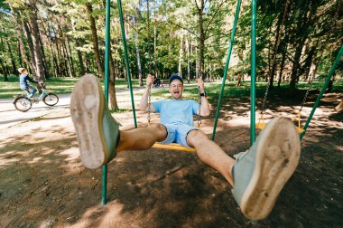 Bahçesi yaz parkta salıncakta sallanan yetişkin adam