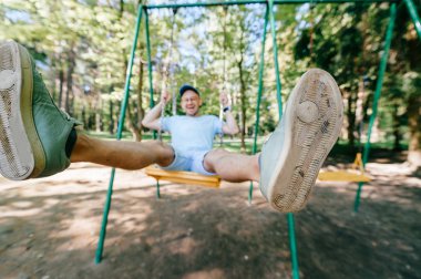 Bahçesi yaz parkta salıncakta sallanan yetişkin adam