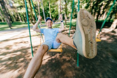 Bahçesi yaz parkta salıncakta sallanan yetişkin adam