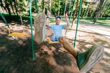 Bahçesi yaz parkta salıncakta sallanan yetişkin adam