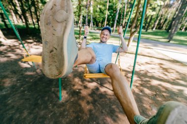 Bahçesi yaz parkta salıncakta sallanan yetişkin adam