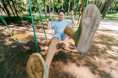 Bahçesi yaz parkta salıncakta sallanan yetişkin adam