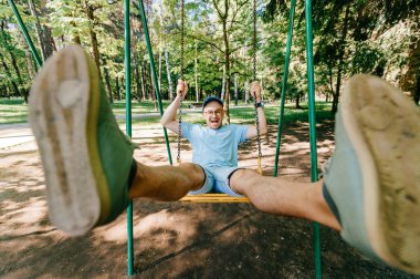 Bahçesi yaz parkta salıncakta sallanan yetişkin adam