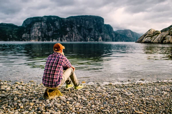 Cestovatelů Muž Džínách Čepici Boty Kámen Fjordu Norsku Vodou Horské — Stock fotografie