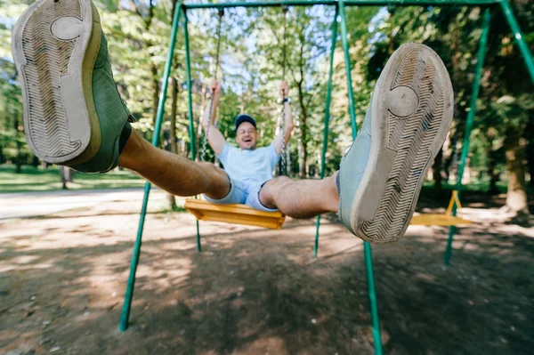 Bahçesi yaz parkta salıncakta sallanan yetişkin adam