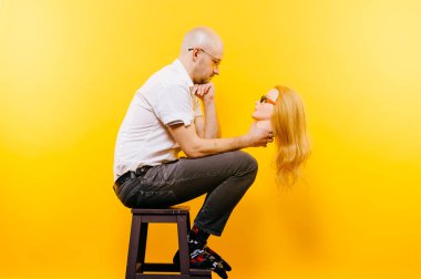 kel adam Sarı zemin tahta sandalyede otururken plastik manken kafa tutan