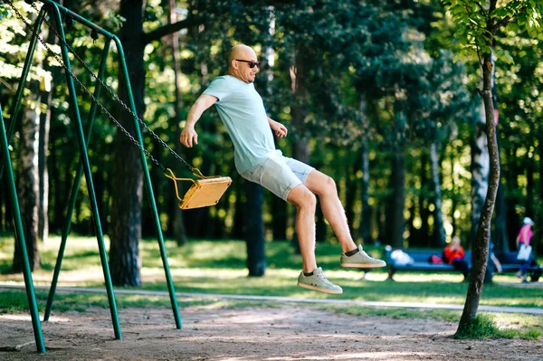 Взрослый Мужчина Прыгает Качелях Детской Площадке Летнем Парке — стоковое фото