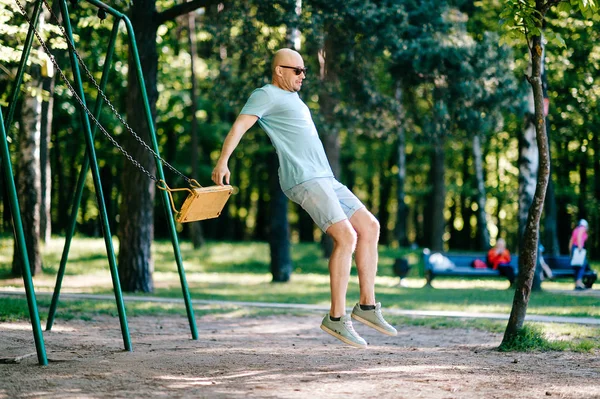 Взрослый Мужчина Прыгает Качелях Детской Площадке Летнем Парке — стоковое фото