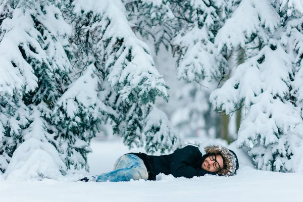 雪に覆われた冬の森の地面に横たわっている男 — ストック写真
