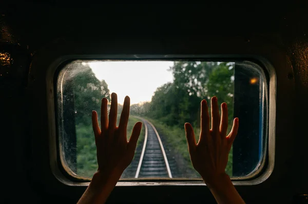 从铁路上乘坐火车到日落时自然景观 可以看到女性手的部分景观和透过窗户的风景 — 图库照片